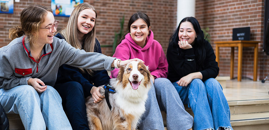 Four female students sitting with a dog.