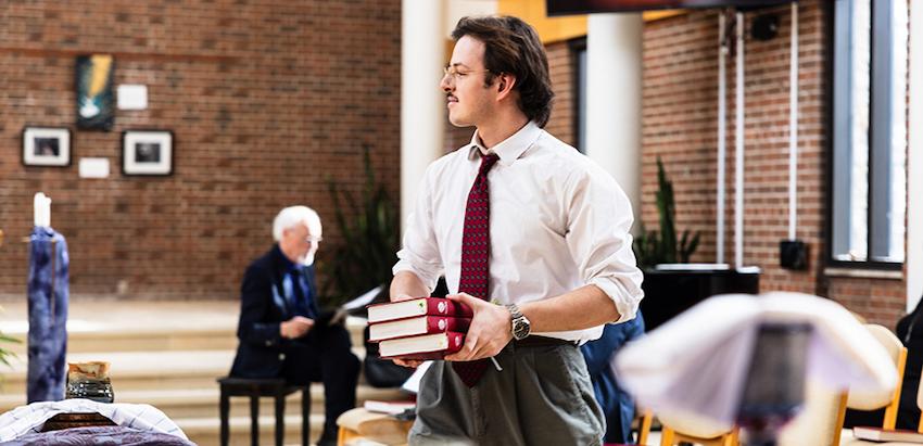 A student carrying books in a chapel