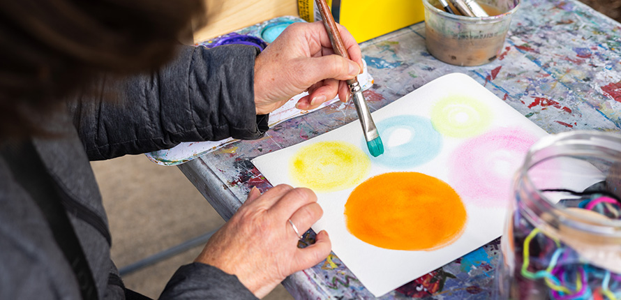 Woman holding a paint brush over a piece of artwork