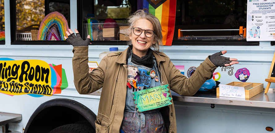 Person smiling with their arms in the air in front of a bus